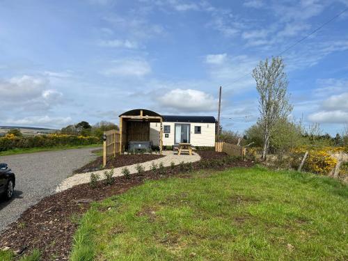 una casa pequeña con un porche al lado de una carretera en Redfox Shepherds hut and private hot tub, en Ballynameen