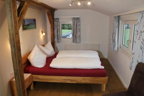 Cama en habitación pequeña con colchón rojo en Burglehnerhof en Ramsau am Dachstein