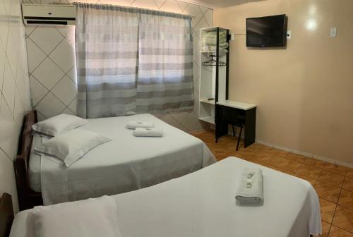 a hotel room with two beds and a television at HOTEL POUSADA POR DO SOL in Pato Branco