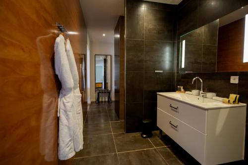 La salle de bains est pourvue d'un lavabo et d'un peignoir blanc. dans l'établissement SWIM LODGE HOTEL Piscine privée ou Jacuzzi privé, à Porto-Vecchio