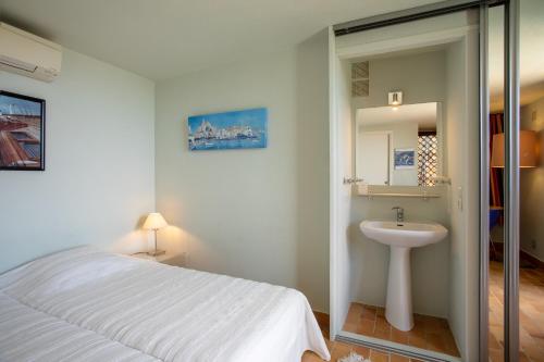 ein Schlafzimmer mit einem weißen Bett und einem Waschbecken in der Unterkunft Maison Piscine Vue mer in Bormes-les-Mimosas