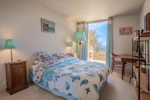 Schlafzimmer mit einem Bett, einem Schreibtisch und einem Fenster in der Unterkunft Maison Piscine Vue mer in Bormes-les-Mimosas