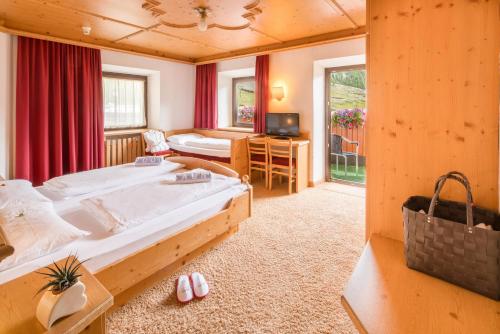 Piccolo Hotel Gurschler في ماسو كورتو: غرفة نوم بسرير ومكتب وتلفزيون