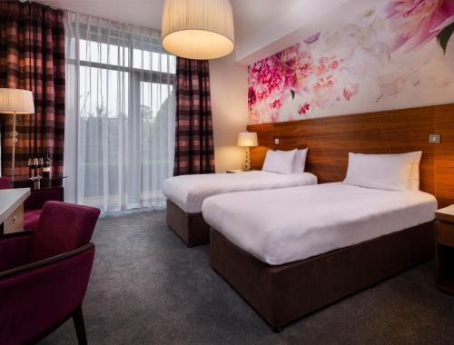 a hotel room with two beds and a chair at Moyvalley Hotel & Golf Resort in Moyvally