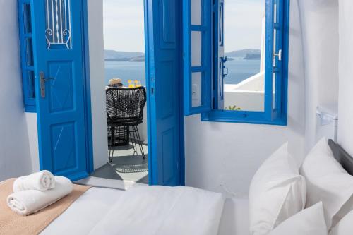 a room with blue doors and a bed and a chair at Luxus VIP Suites in Oia
