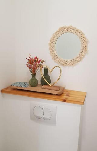 - une étagère en bois avec un miroir et un vase dans l'établissement Appartement Kiel - Secret Beach - La Croix Valmer, à La Croix-Valmer