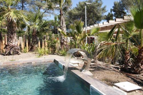 - une piscine avec une fontaine dans une cour agrémentée de palmiers dans l'établissement Appartement Kiel - Secret Beach - La Croix Valmer, à La Croix-Valmer