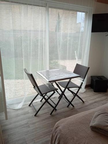 einen Tisch und zwei Stühle in einem Zimmer mit Fenster in der Unterkunft L'ANNEXE in Chaumont