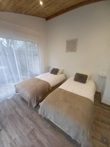 2 Betten in einem Zimmer mit Fenster in der Unterkunft L'ANNEXE in Chaumont