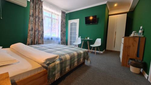 a bedroom with green walls and a bed and a table at CryptoHotel.Club in Almaty