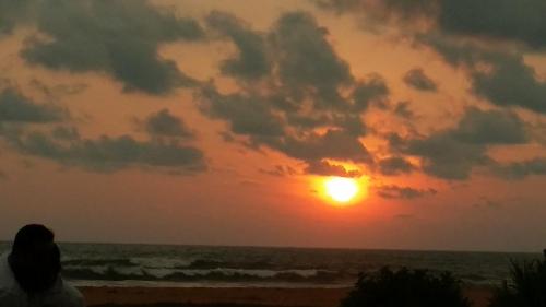 a person sitting on the beach watching the sunset at Sunset Beach Residence in Panadura