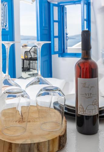 a bottle of wine next to glasses on a table at Luxus VIP Suites in Oia