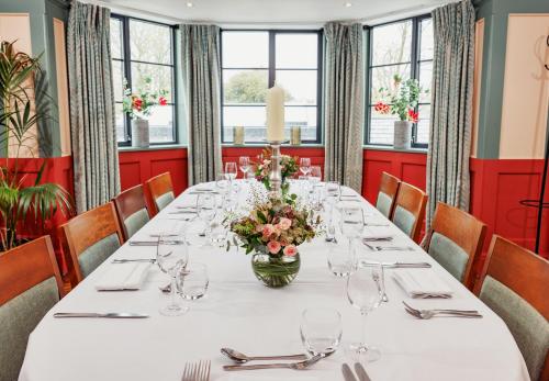 a dining room with a long table with a vase of flowers at The High Field Town House in Birmingham