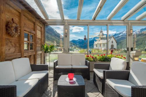 a conservatory with chairs and tables and a view of a castle at Piccolo Hotel Gurschler in Maso Corto