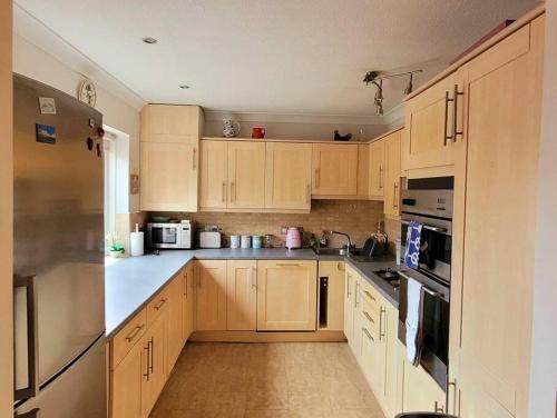 a kitchen with wooden cabinets and white appliances at Hot Tub Beach Bungalow - free parking & child friendly in South Hayling