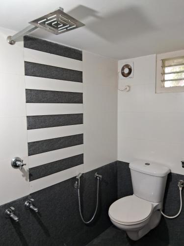 a bathroom with a toilet and black and white stripes at Mi Casa Tu Casa Homestay in Ernakulam