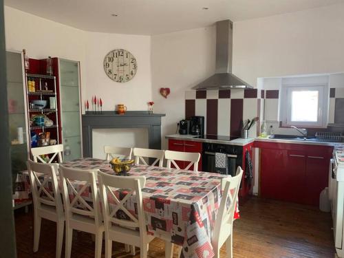 a kitchen with a table with chairs and a clock on the wall at Maison Centrale in Ax-les-Thermes