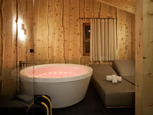 a bathroom with a tub and a bench in a room at Dolomiti Lodge Alver&agrave; in Cortina dʼAmpezzo