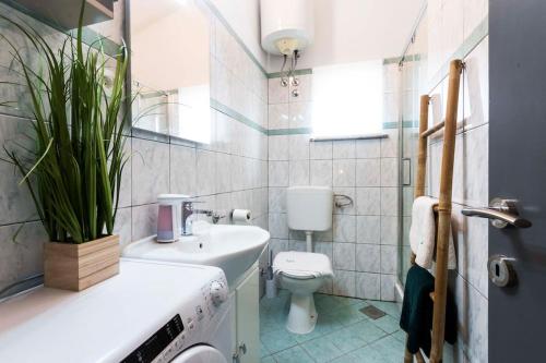 Un baño con un lavabo blanco y un inodoro. en Apartman Smaragd, en Fažana