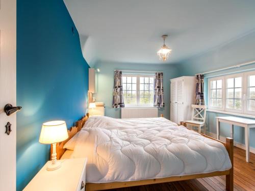 ein blaues Schlafzimmer mit einem großen Bett und einem Schreibtisch in der Unterkunft Renovated Hortensia Villa with a unique location next to the dunes in Koksijde
