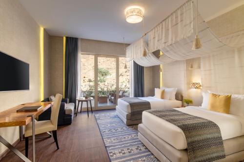 a hotel room with two beds and a desk at Shaden Resort in AlUla