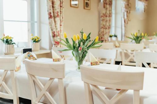 クルティンにあるGościniec Mazurのダイニングルーム(白い椅子、黄色い花のテーブル付)