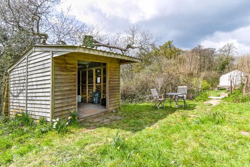 um pequeno barracão num campo com uma mesa em Lower Marsh Farm in Cornwall em Saltash