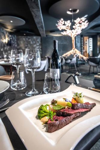 a plate of food on a table with wine glasses at Logis Hôtel Restaurant Gilles Moreau Laguiole in Laguiole