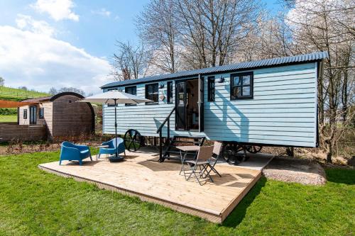 a blue trailer with a deck with a table and chairs at Vakantiepark Vinkenhof in Schin op Geul
