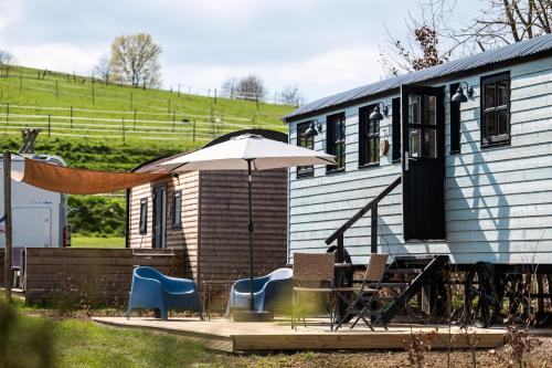 a patio with chairs and an umbrella and a house at Vakantiepark Vinkenhof in Schin op Geul