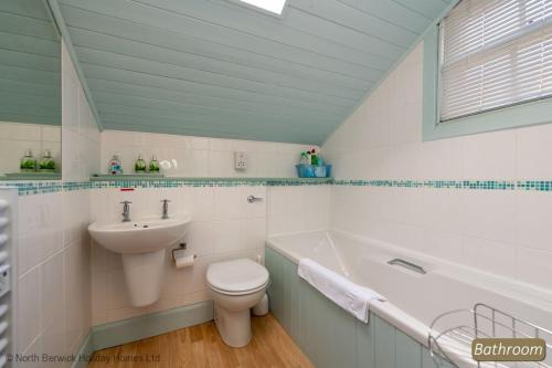 La salle de bains est pourvue d'un lavabo, de toilettes et d'une baignoire. dans l'établissement Puffling Cottage, à North Berwick