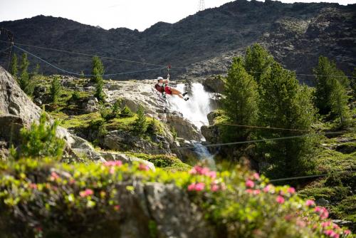 a man on a suspension bridge over a waterfall at Piccolo Hotel Gurschler in Maso Corto