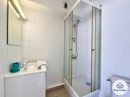ein weißes Bad mit einer Dusche und einem Waschbecken in der Unterkunft Anjou 1 - studio de 20 m2 à Saint-Denis in Saint-Denis