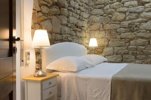 a bedroom with a white bed with a stone wall at B&B Le Stanze di Ludovica in Termoli