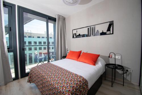 Ekilibrio Hotel & Apart-Suites في مدريد: غرفة نوم مع سرير مع وسائد برتقالية وشرفة