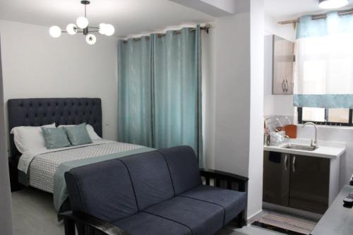 a bedroom with a bed and a couch and a sink at Lux Suites Royal Gardens Studio Apartments in Nairobi