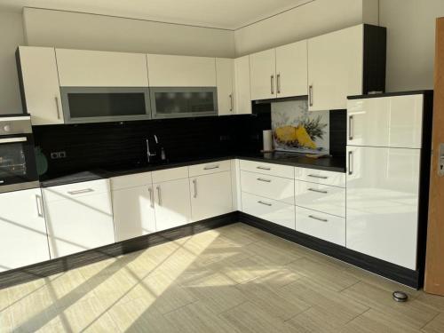 una cocina con armarios blancos y encimeras negras en Marina, Ferienwohnung, en Schneverdingen