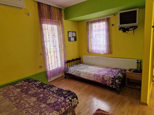 a bedroom with two beds and a flat screen tv at Apartments Hadži in Soko Banja