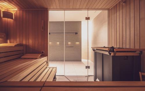 - une douche en verre dans une chambre dotée de murs en bois dans l'établissement Parsenn Resort, à Davos