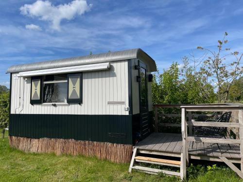 a green and white tiny house with a chair at De la Rue Pipowagens in Sleeuwijk