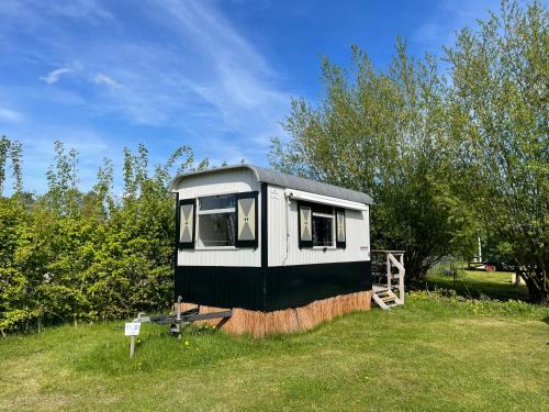 a black and white tiny house in a field at De la Rue Pipowagens in Sleeuwijk