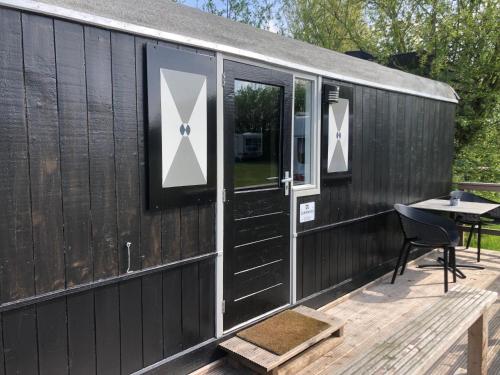 a black house with a table on a deck at De la Rue Pipowagens in Sleeuwijk