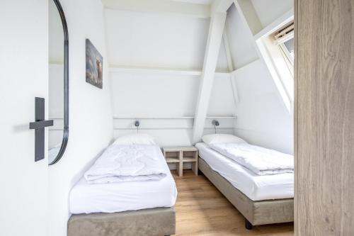 two beds in a small room with a cross on the wall at Appartementen Beatrix in De Koog