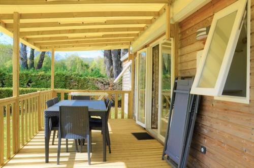 une terrasse avec une table, des chaises et une télévision dans l'établissement Camping Les Mijeannes, à Rieux-de-Pelleport