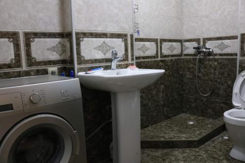 uma casa de banho com um lavatório e uma máquina de lavar roupa em York Tower em Tbilisi