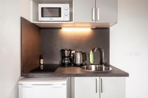 a kitchen counter with a sink and a microwave at Séjours & Affaires Paris Vincennes in Vincennes