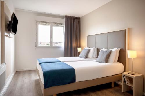 ein Hotelzimmer mit einem großen Bett und einem Fenster in der Unterkunft Séjours & Affaires Paris Vincennes in Vincennes