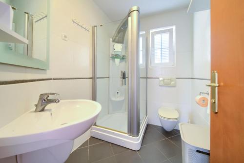 a white bathroom with a sink and a shower at Apartment Camellia in Vantačići