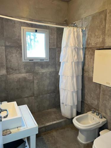 baño con aseo y lavabo y ventana en Sporthaus.costaesmeralda en Pinamar