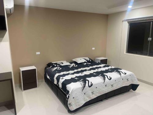 a bedroom with a bed with a black and white comforter at Hermosa Casa Minimalista cerca a la Naturaleza in Cochabamba